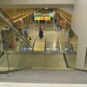 Pohled ze schodiště do přestupní chodby na nástupiště trasy A s kioskem výtahu do přestupní chodby a na nástupiště trasy B